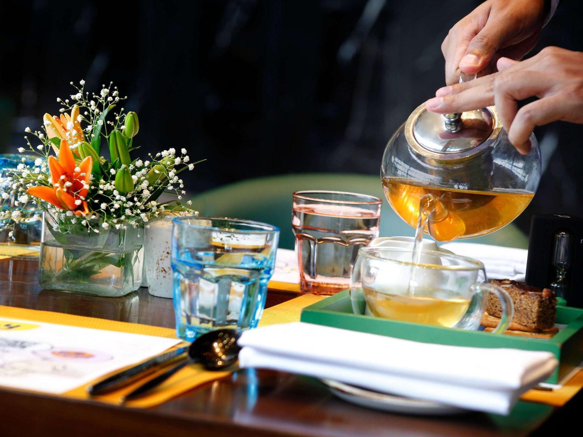 Novotel Kolkata Hotel And Residences Kültér fotó A server pours tea at a restaurant